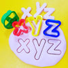 x y z stamped into and cut out from playdough using alphabet cutters.