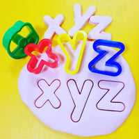 x y z stamped into and cut out from playdough using alphabet cutters.