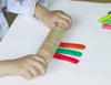 child rolling playdough with wooden rolling pin