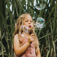 child blowing bubbles with rabbit wand