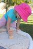 girl playing with wooden stamper in sand